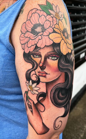 A tattoo of a woman with flowers in her hair